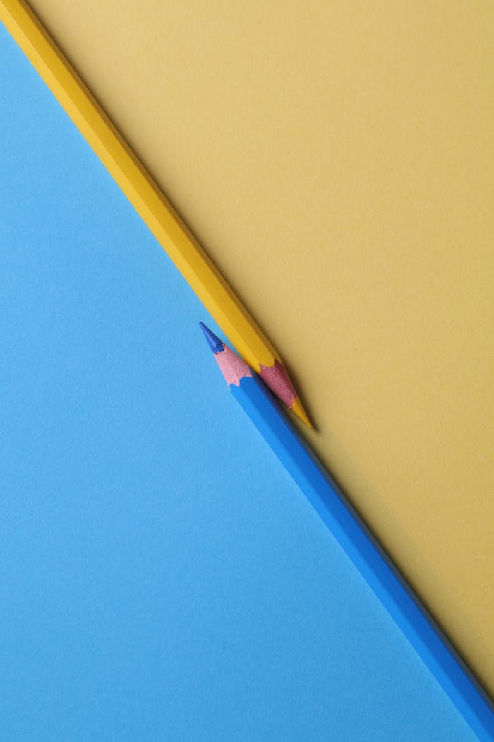 about-us-02 Close-up of vibrant yellow and blue colored pencils on contrasting paper backgrounds.